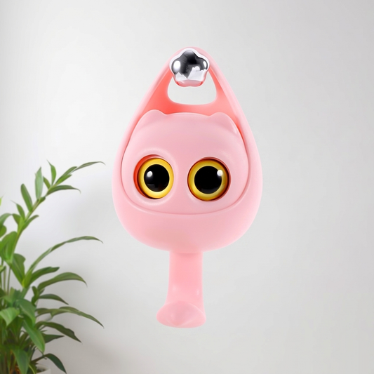 Close-up of a cute pink cat-shaped wall hook with large expressive eyes mounted on a white wall