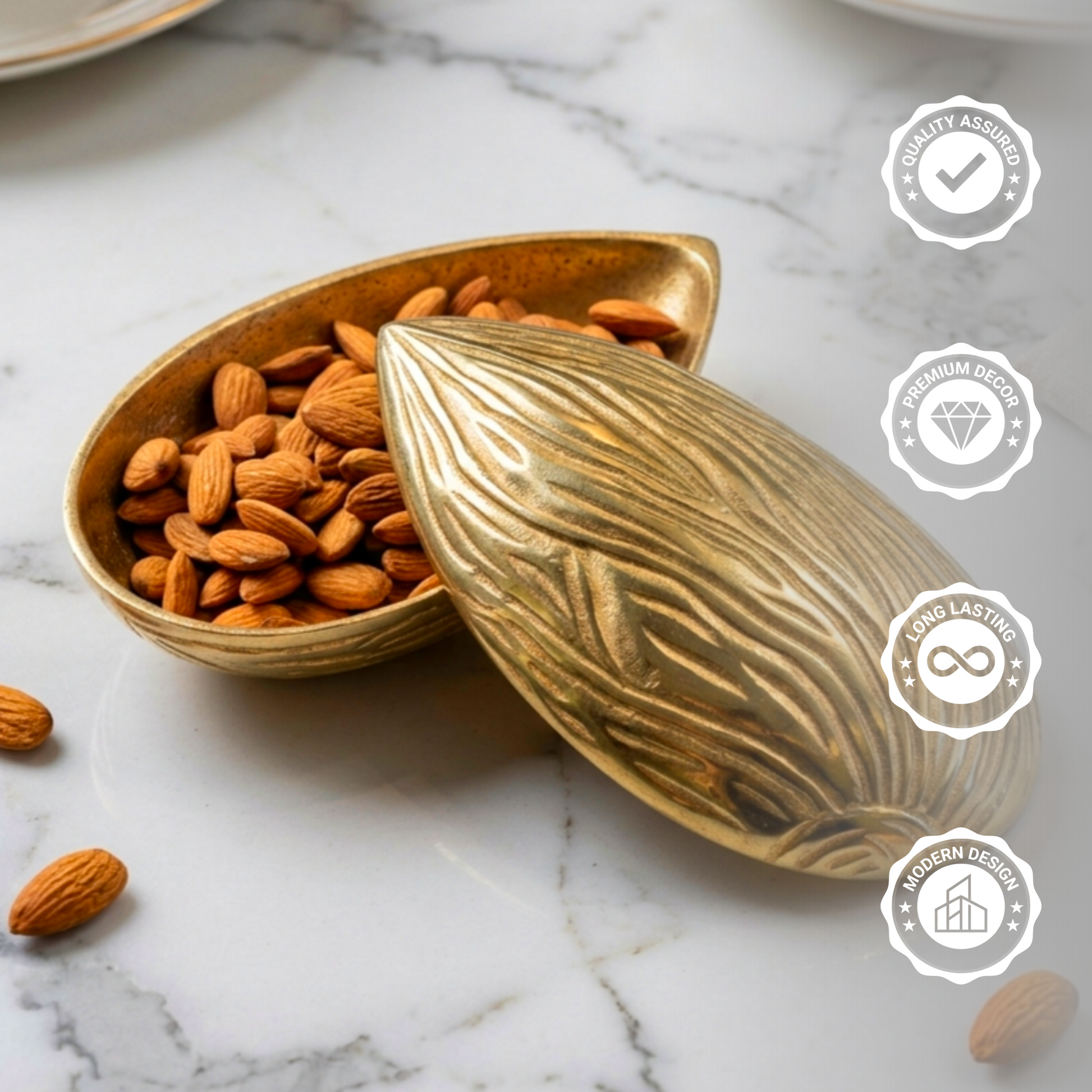 Golden brass storage bowl shaped like a textured almond, partially open with its lid resting to the side, filled with raw almonds and placed on a white marble countertop.