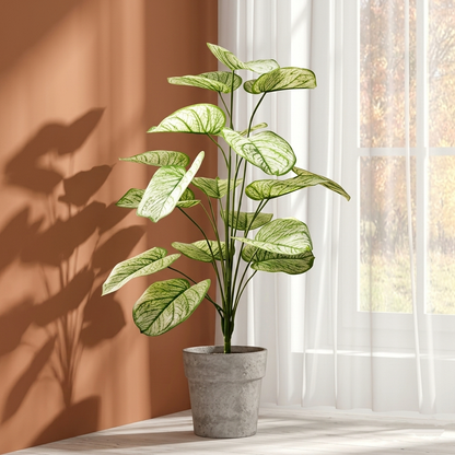 Large artificial White Caladium faux houseplant styled indoors near a sunlit window with terracotta walls.