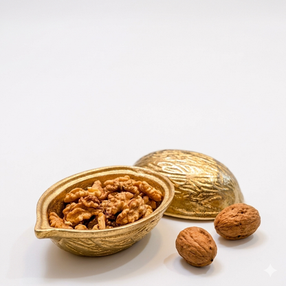 Studio shot of a two-piece metallic gold decorative bowl shaped like a large walnut, open to reveal actual walnuts inside against a solid white background.